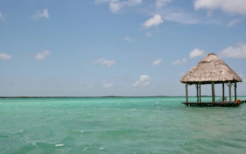 brown wooden beach house on blue sea under blue sky during daytime — Bacalar