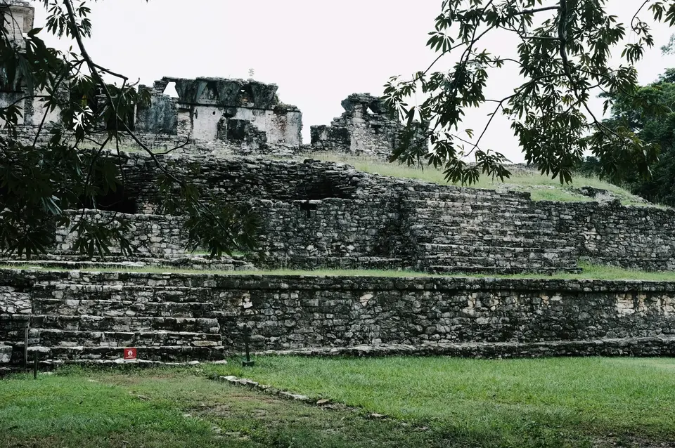 a large stone structure sitting on top of a lush green field — Cancún