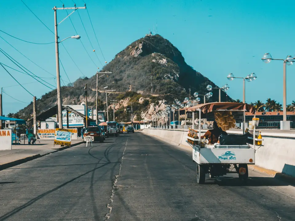 white auto rickshaw on riding on asphalt road towards green mountain — Mazatlán