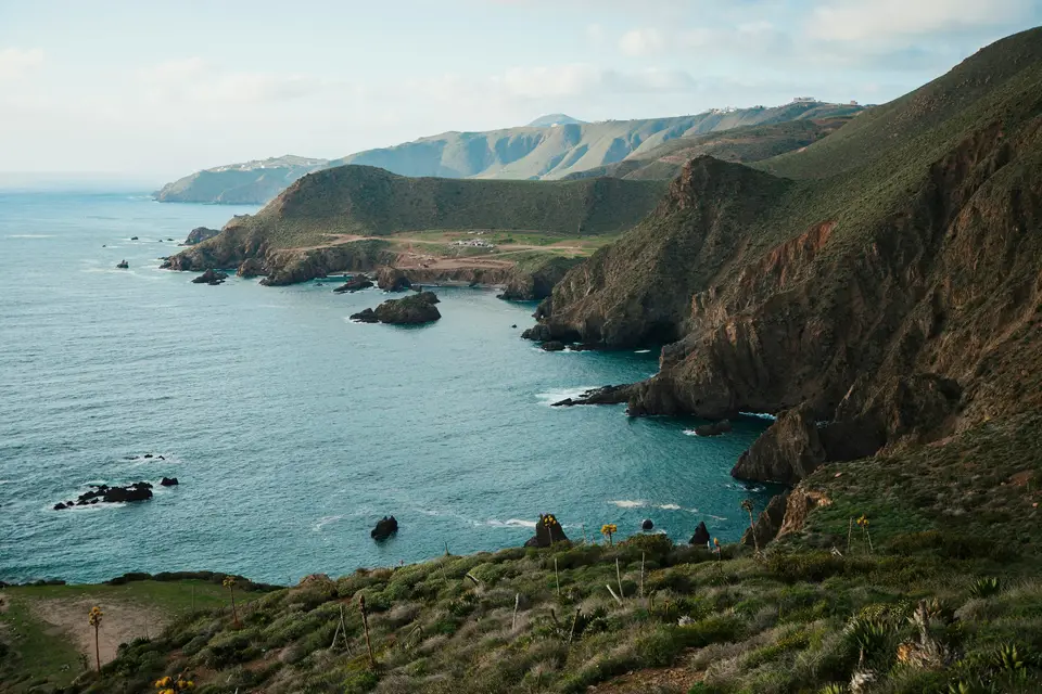 a body of water surrounded by mountains and greenery — Todos Santos