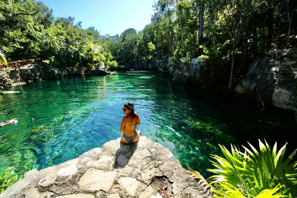 woman in black bikini sitting on rock near body of water during daytime — Tulum