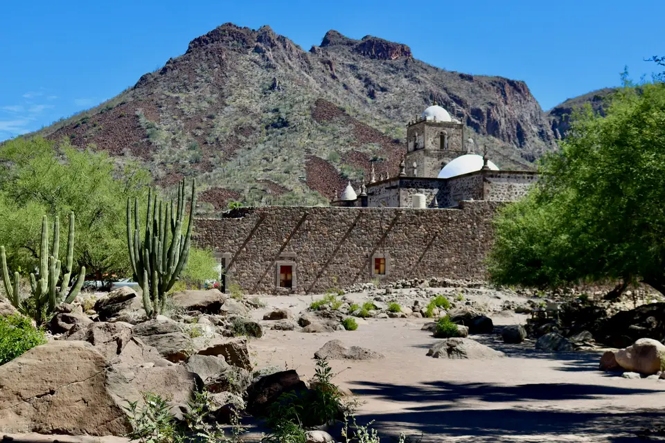Stone building with desert plants and mountains behind — Valle de Guadalupe