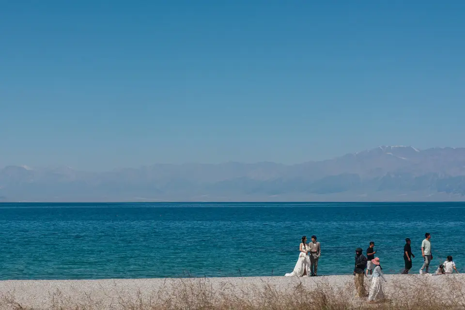 People gathered on a wall by the blue ocean